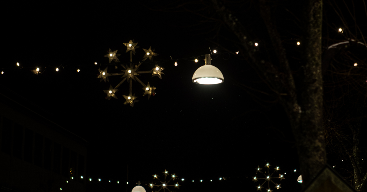 En kupformad lampa hänger bredvid en stjärnformad julgirlang som lyser i mörkret.